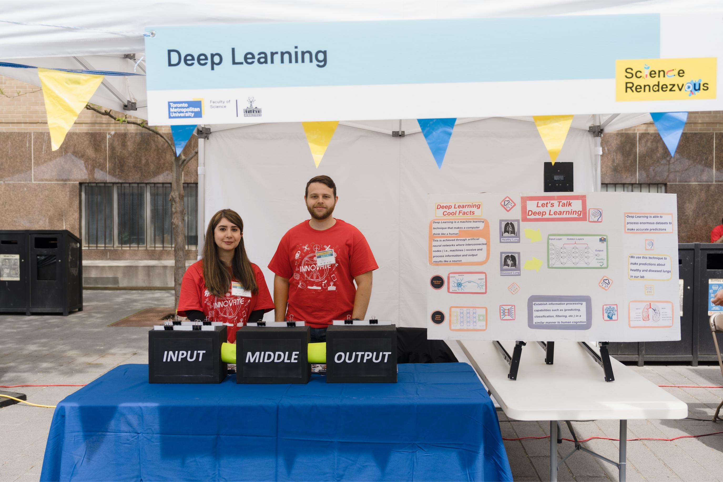 Two volunteers posing at the Deep Learning Booth.